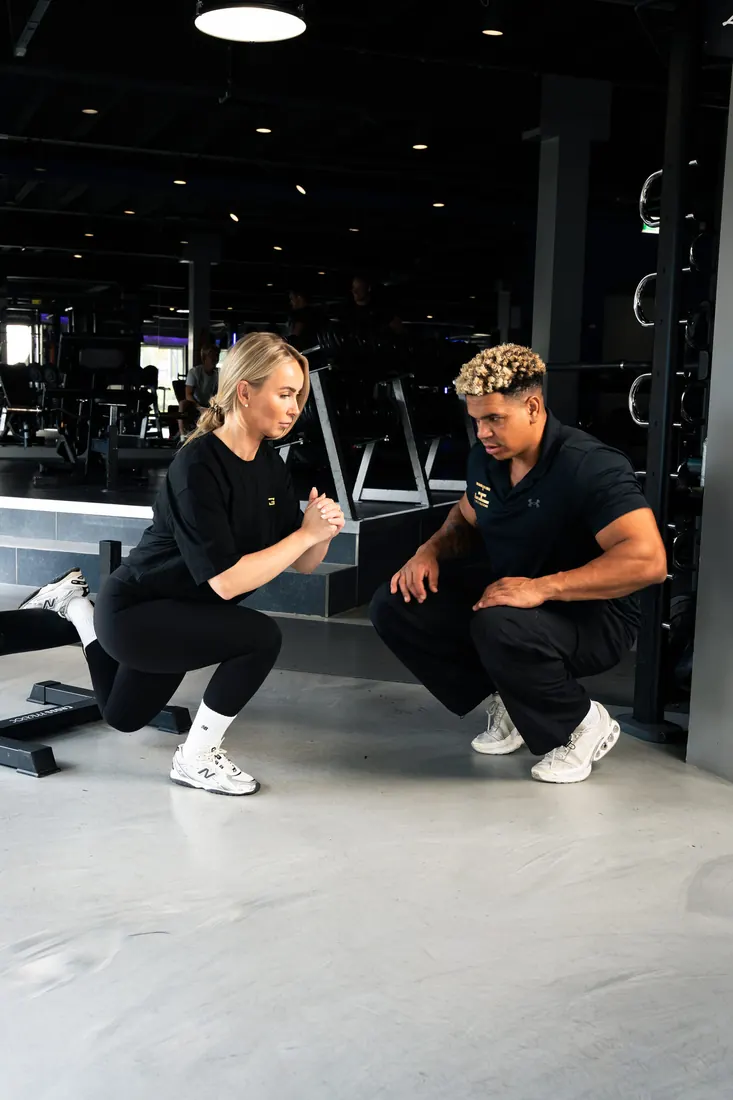 Personal trainer legt een oefening uit